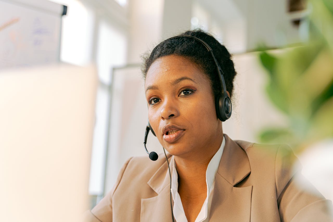 African American woman working in a call center with a headset on, providing customer support.